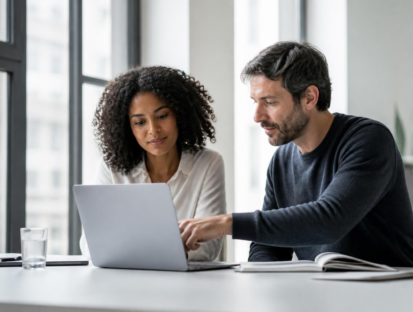 Two colleagues looking at a laptop together in a bright office